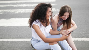 Female teenage friends looking at smartphone