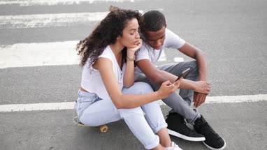 Teenage boyfriend and girlfriend looking at smartphone