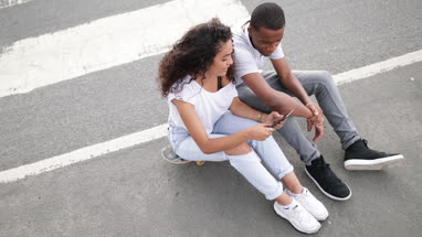 Teenage boyfriend and girlfriend looking at smartphone