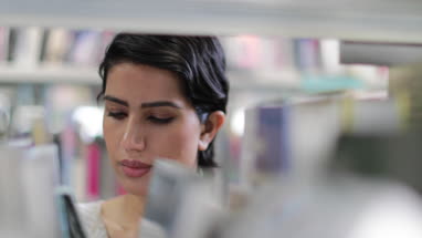 Arabic female student choosing book in library