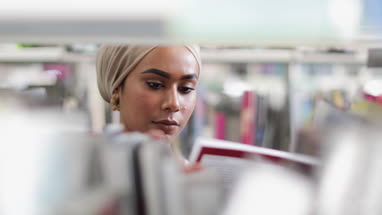 Muslim female student choosing book in library