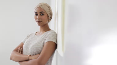 Muslim teacher leaning against whiteboard in a classroom