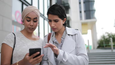 Muslim friends using a smartphone on a shopping trip