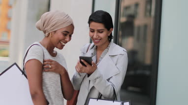Muslim friends using a smartphone on a shopping trip