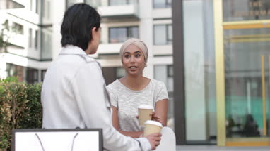 Female Muslim friends having coffee together outdoors