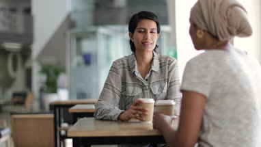 Female Muslim co-workers having coffee together