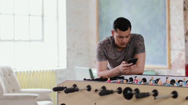 Young adult male using smartphone in a creative office