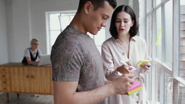 Young adults brainstorming in a creative office with adhesive notes