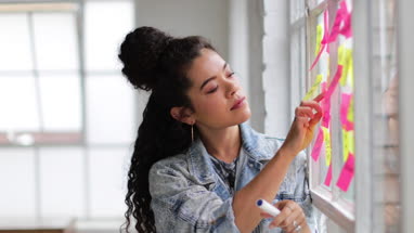 Portrait of young adult female brainstorming in a creative office with adhesive notes