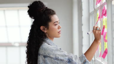 Portrait of young adult female brainstorming in a creative office with adhesive notes