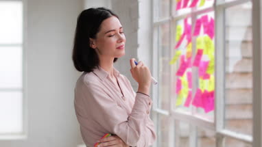 Portrait of young adult female brainstorming in a creative office with adhesive notes