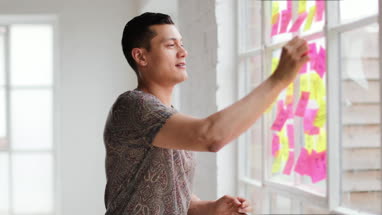 Portrait of young adult male brainstorming in a creative office with adhesive notes