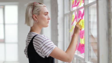 Portrait of young adult female brainstorming in a creative office with adhesive notes