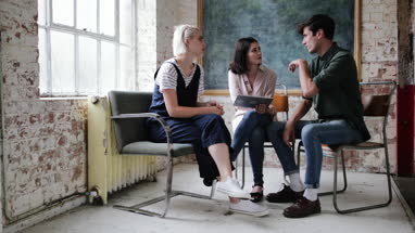 Young adults in a meeting in a creative studio with a digital tablet