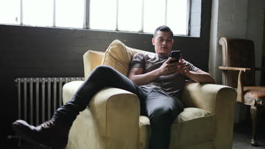 Millennial using smartphone in a loft apartment