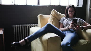 Millennial using smartphone in a loft apartment
