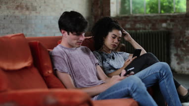 Millennials using smartphones relaxing on sofa