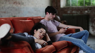 Millennials using smartphones relaxing on sofa