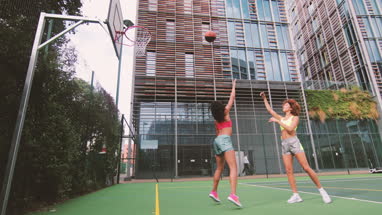 Young adult female basketball player scoring a hoop