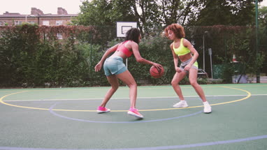 Young adult females playing basketball