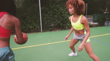 Young adult females playing basketball