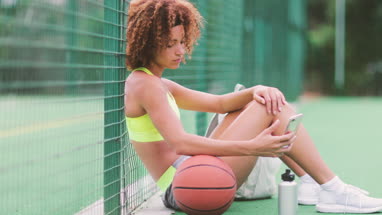 Young adult female on a basketball court using smartphone