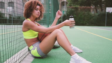 Young adult female sitting on a basketball court