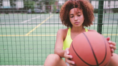 Young adult female sitting on a basketball court