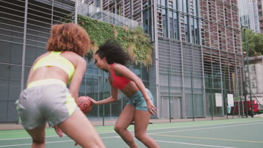 Young adult females playing basketball