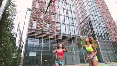 Young adult females playing basketball