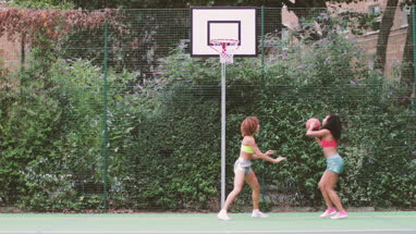 Young adult females playing basketball