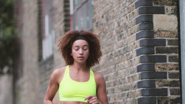 Young adult female checking activity tracker on a run in urban city