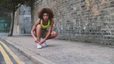 Young adult female tying shoe lace before a run