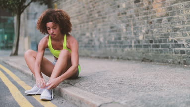 Young adult female tying shoe lace before a run