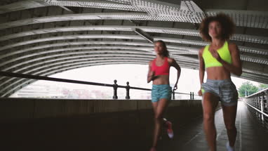 Young adult female friends running together in an urban environment