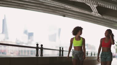 Young adult female friends running together in an urban environment