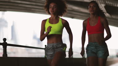 Young adult female friends running together in an urban environment