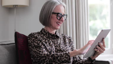 Mature adult female happily using a digital tablet