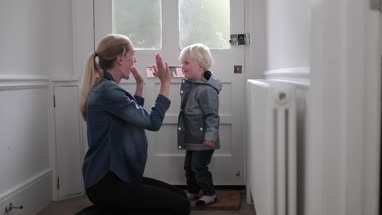 Mother helping child put on a coat