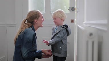 Mother helping child put on a coat