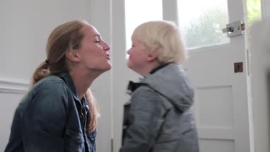 Mother and child kissing goodbye at home