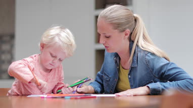 Mother and child drawing together with colored pencils