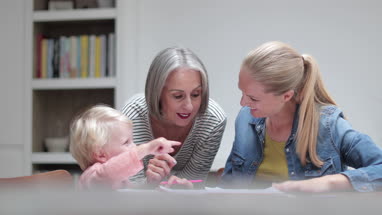 Boy showing his drawing to grandmother and mother