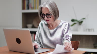 Mature adult female paying bill online using a laptop