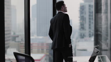 Businessman looking up at skyscraper thinking