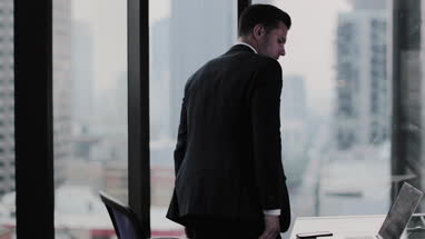 Businessman looking out at city skyline thinking