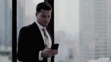 Businessman using smartphone in skyscraper office