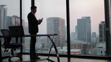 Businessman using smartphone in skyscraper office