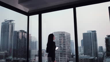 Businesswoman working late using smartphone with city skyline in background