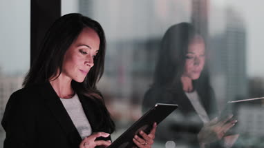 Businesswoman and reflection working late using digital tablet